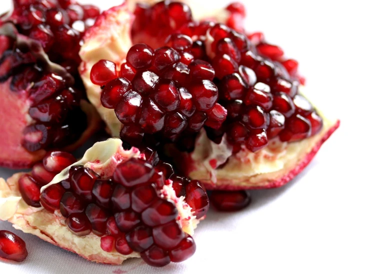 a close up of a pomegranate on a plate, productphoto, persian princess, squashed berries, with a white background