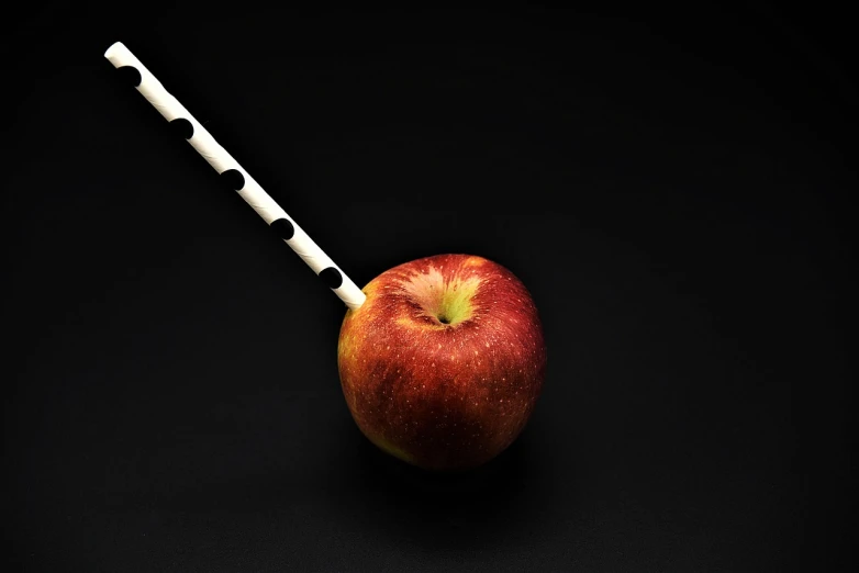 an apple with a fork sticking out of it, inspired by Orazio Gentileschi, hyperrealism, esthetic photo, chopsticks, with a straw, red black white colors