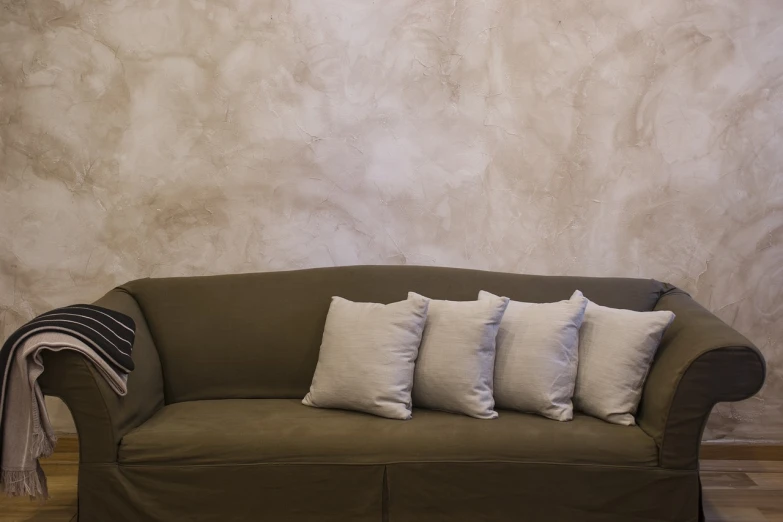 a couch sitting on top of a hard wood floor, by Elsa Bleda, pixabay, art nouveau, light beige pillows, before a stucco wall, weathered olive skin, stylishly designed background