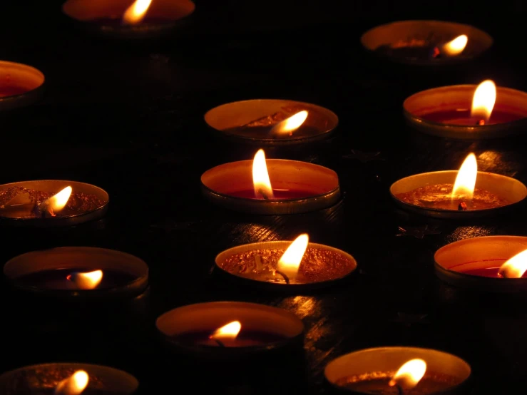 a group of lit candles sitting on top of a table, a picture, pexels, digital art, detailed zoom photo, against a deep black background, high res photo, emitting light ornaments