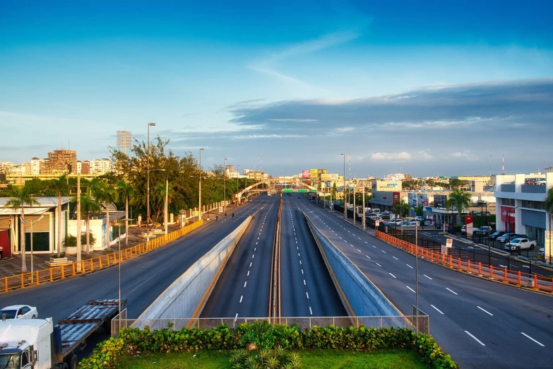 a city street filled with lots of traffic next to tall buildings, a stock photo, shutterstock, overpass, puerto rico, during dawn, ultra wide horizon