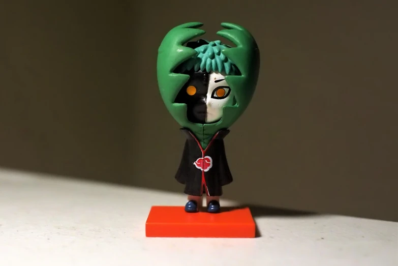 a close up of a toy on a table, inspired by Ryuzaburo Umehara, vanitas, green face, chibi style, very very low quality picture, single head