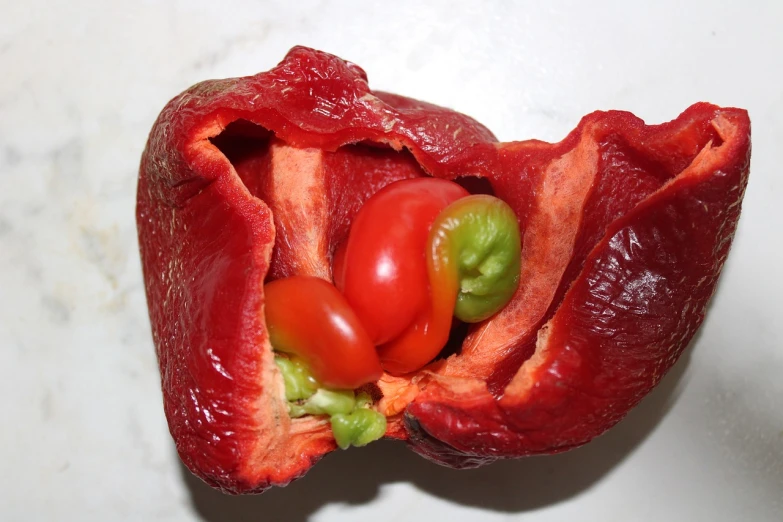 a red pepper with a green tomato inside of it, by Jan Rustem, tumblr, dada, internal organs, closeup - view, upon a peak in darien, which splits in half into wings