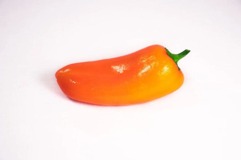 an orange pepper sitting on top of a white surface, rasquache, miniature product photo, highly detailed soft lighting, productphoto, arizona