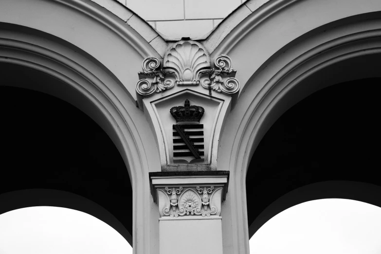 a clock that is on the side of a building, a black and white photo, baroque, resembling a crown, impressive detail : 7, archway, architecture photo