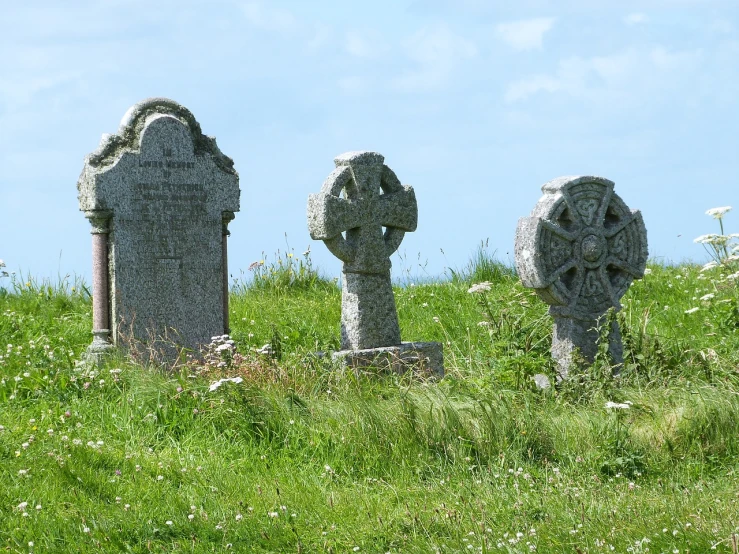 a group of tombstones sitting on top of a lush green field, by Alison Watt, flickr, coastal, celtic knots, 3 heads, deteriorated