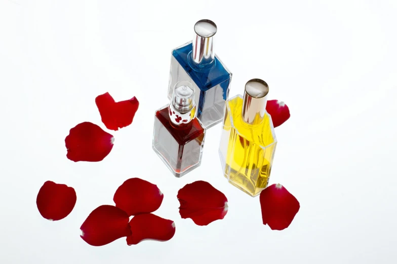 a couple of perfume bottles sitting on top of a table, a still life, large individual rose petals, professional product photo