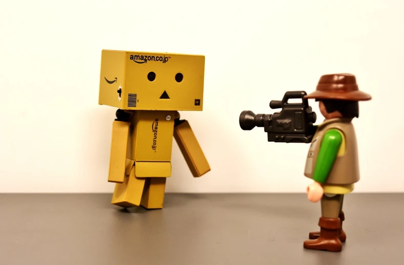 a couple of action figures standing next to each other, a picture, by Edward Corbett, unsplash, neo-dada, robot made of a cardboard box, the teddy bear is holding a gun, amazon, television head