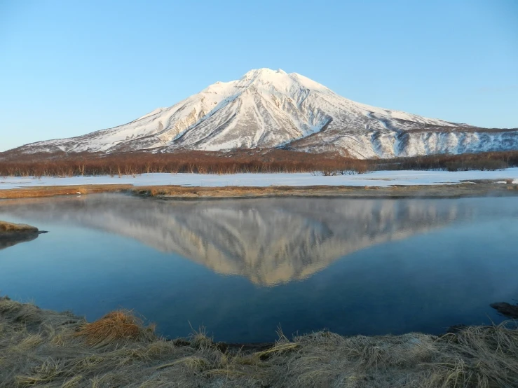 a body of water with a mountain in the background, a picture, by Andrei Kolkoutine, flickr, sōsaku hanga, spring winter nature melted snow, yuruyuri, mirrored, active volcano