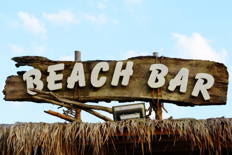 a sign that says beach bar on top of a thatched roof, by James Ballantine, pixabay, detail shots, driftwood, kit bash, bali