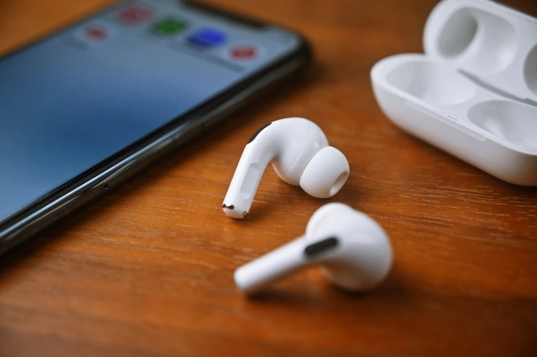 a pair of airpods sitting on top of a wooden table next to a cell phone, happening, photo shot, thumbnail