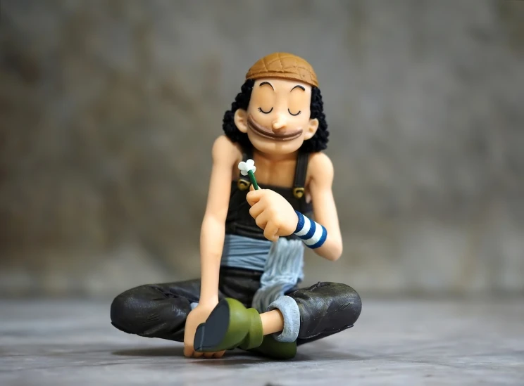 a figurine of a man sitting on a rock, a picture, inspired by Eiichiro Oda, don ramon, starving artist wearing overalls, <hd, serene smile