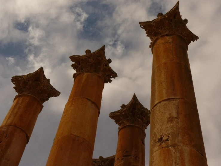 a group of pillars sitting next to each other under a cloudy sky, by Steven Belledin, romanesque, arabic, documentary still, beware the ides of march, bottom angle