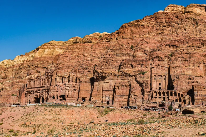 a group of buildings carved into the side of a mountain, by Cafer Bater, shutterstock, jordan, 1128x191 resolution, wide long view, usa-sep 20