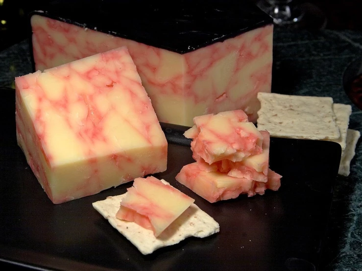 a black plate topped with cheese and crackers, by Jon Coffelt, flickr, carved soap, marbling effect, reds, blushing