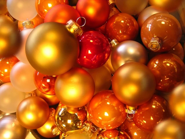 a pile of christmas ornaments sitting on top of a table, a picture, by Eugeniusz Zak, gradient yellow to red, warm saturatured colors, shiny!!, yellow-orange