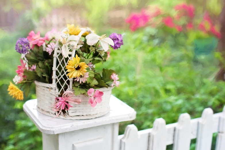 a basket of flowers sitting on top of a white fence, pixabay contest winner, tilt shift background, cute style garden, seasons!! : 🌸 ☀ 🍂 ❄, flower shop scene