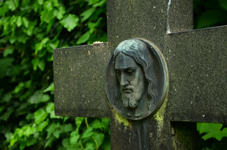 a close up of a cross with a face on it, by Jacek Sempoliński, green head, jesus, cementary, david a