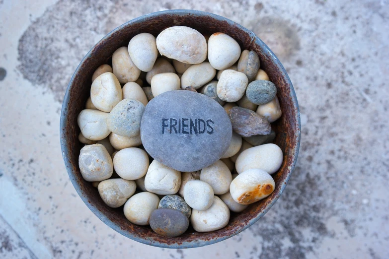 a bowl filled with rocks and a stone with the word friends written on it, pexels, istock, stock photo