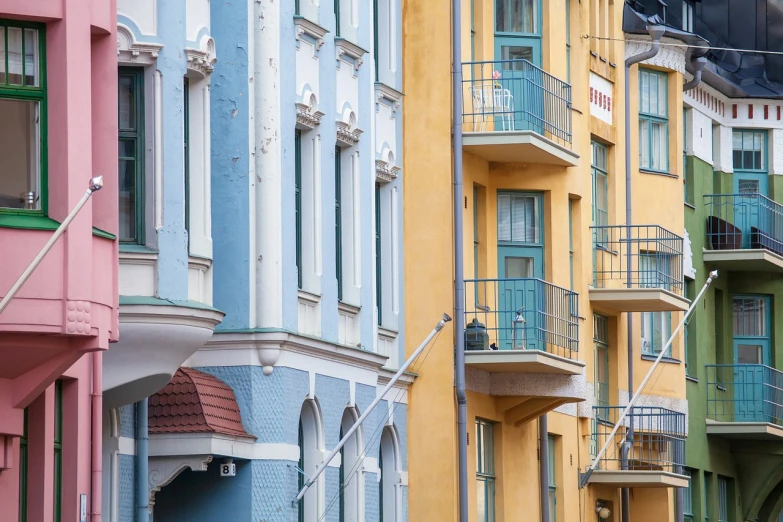 a row of multicolored buildings with balconies, a photo, inspired by Wilhelm Marstrand, art nouveau, yellow and cyan color palette, scandinavian, sand - colored walls, neo - classical