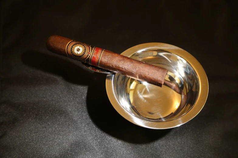 a cigar sitting on top of a metal ashtray, inspired by Ceferí Olivé, hurufiyya, selk ´ nam god of the sun, dark setting, bowl, ground level