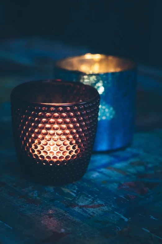 a close up of a lit candle on a table, pexels, pointillism, prussian blue and venetian red, copper cup, cyberpunk pincushion lens effect, metallic polished surfaces