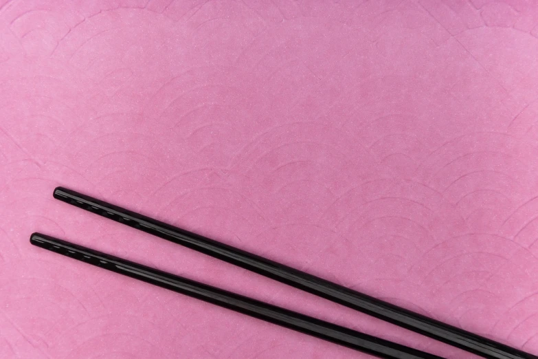 two chopsticks sitting next to each other on a pink surface, flickr, sōsaku hanga, curving black, close-up product photo, handcrafted paper background, high resolution product photo