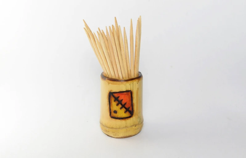 a close up of a toothpick in a cup, folk art, ocher, product photo, bamboo, rectangular