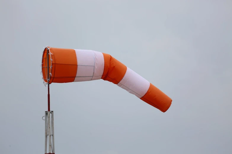 a large orange and white kite flying in the sky, a photo, cannon photo, construction, cold stormy wind, portlet photo