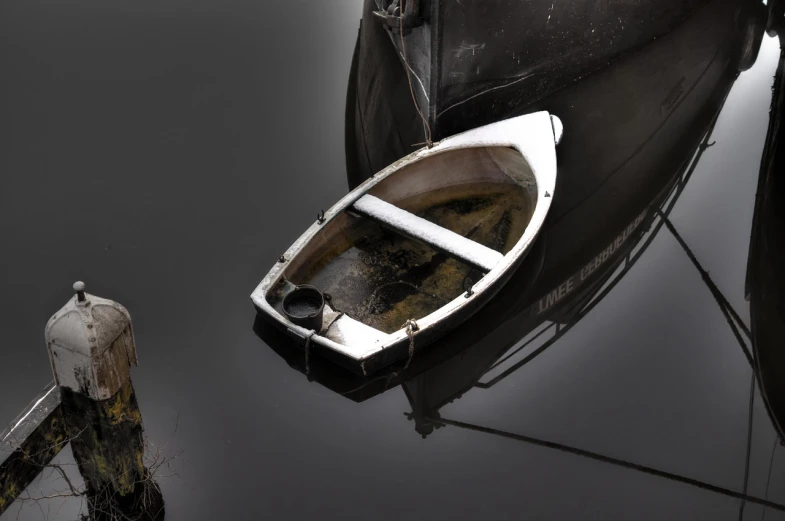 a small white boat sitting on top of a body of water, a photo, by John Murdoch, flickr, covered with liquid tar. dslr, realistic reflection, harbour, dark dingy