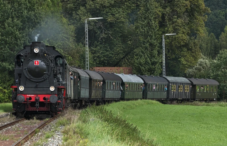 a train traveling down train tracks next to a lush green field, a portrait, by Werner Gutzeit, pixabay, art nouveau, group photo, set in ww2 germany, vintage - w 1 0 2 4, panorama