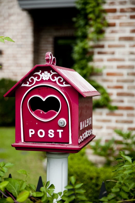 a red mail box sitting in front of a brick building, a photo, by Marten Post, unsplash, pink, fairy tale, kiss, hut