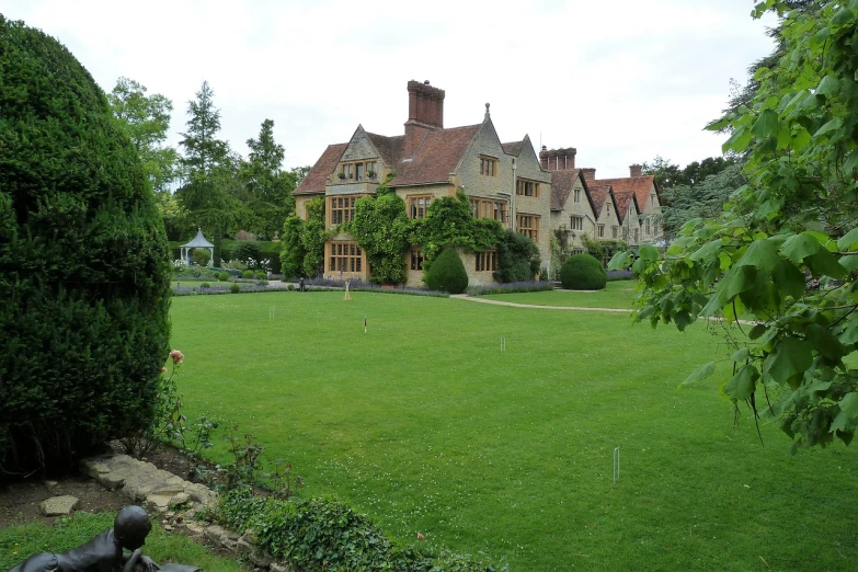 a statue sitting on top of a lush green field, arts and crafts movement, tudor architecture, long shot from the back, lawns, july 2 0 1 1