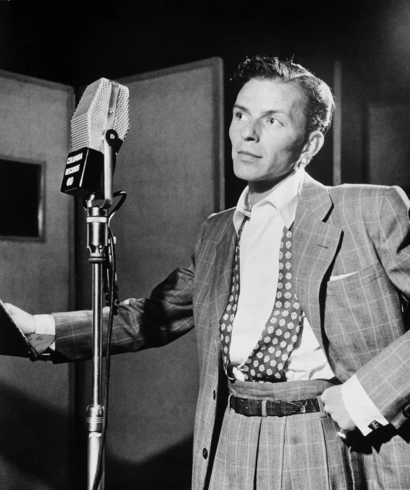 a man in a suit standing in front of a microphone, a portrait, by Howard Knotts, flickr, frank sinatra, getty images, tyler, romance