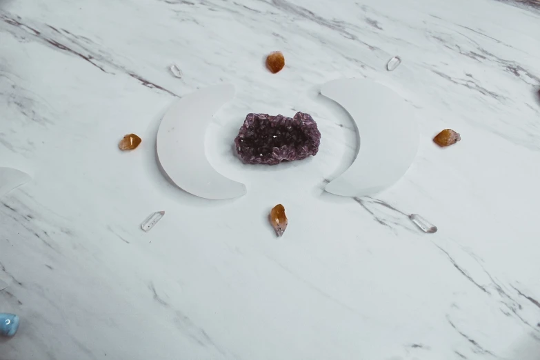 a close up of a plate of food on a table, a marble sculpture, unsplash, vanitas, amethyst mineral quartz, two moons, white backdrop, transparent celestial light gels