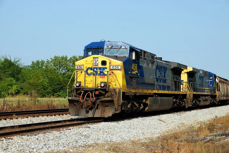 a blue and yellow train traveling down train tracks, by Tom Carapic, diesel engine, high quality product image”