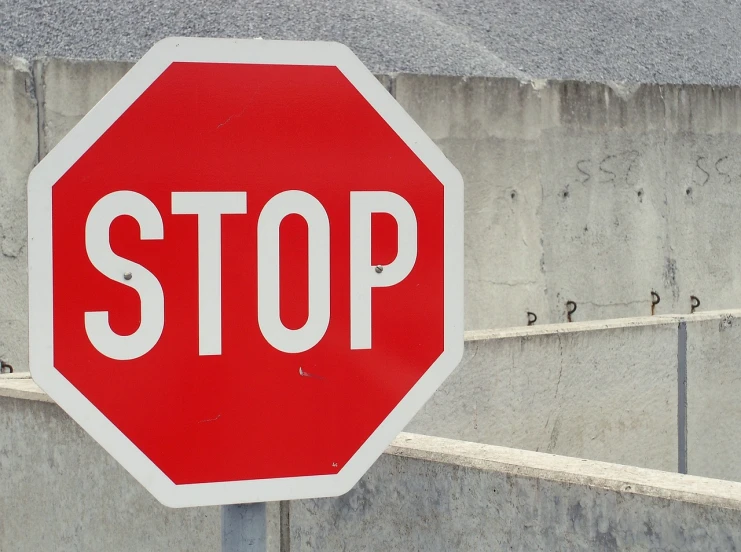 a stop sign in front of a concrete wall, flickr, [ [ hyperrealistic ] ], slow, action still, broadshouldered