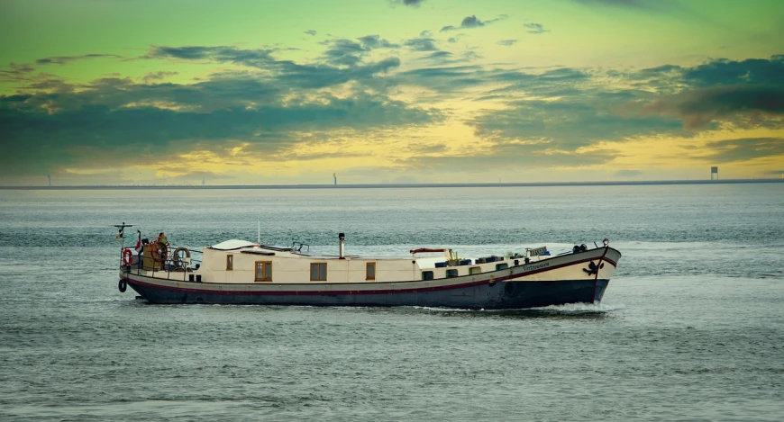 a large boat floating on top of a body of water, a photo, by Michiel van Musscher, shutterstock, in a gentle green dawn light, maintenance photo, dutch style, trailer