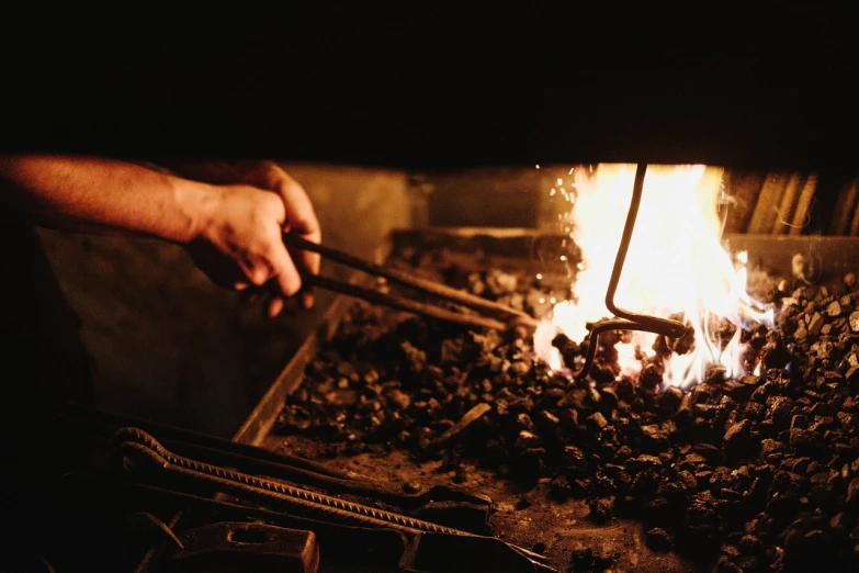 a person holding a pair of tongs in front of a fire, an engraving, by Jörg Immendorff, pexels, jaquet droz, mining, studious chiaroscuro, bottom angle