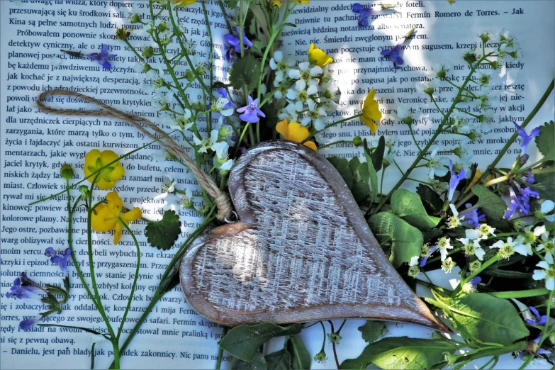 a bunch of flowers sitting on top of an open book, a picture, inspired by János Valentiny, pixabay contest winner, folk art, heartstone, wooden decoration, hay, close - up profile