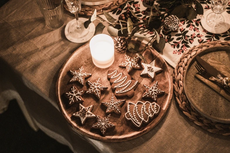 a plate of cookies and a candle on a table, by Caroline Mytinger, pexels, folk art, detailed carved ornaments, glowing stars, brown and white color scheme, cosy vibes