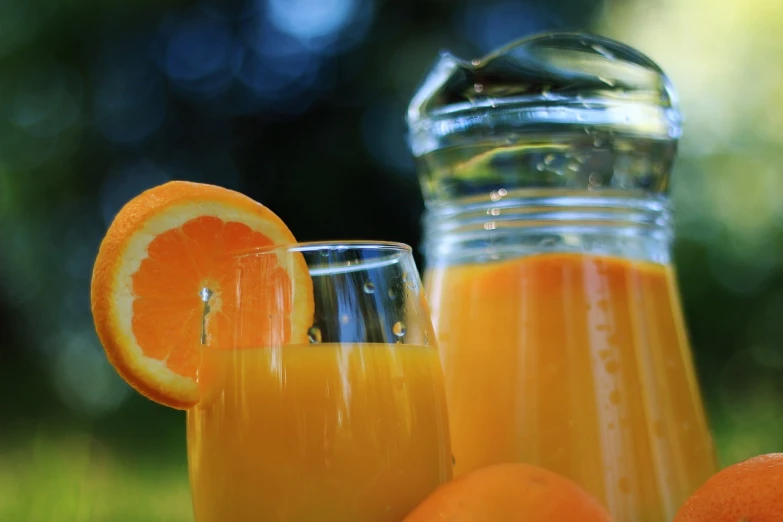 a pitcher of orange juice next to a glass of orange juice, by Jan Rustem, pixabay, picnic, 🦩🪐🐞👩🏻🦳, full frame shot, looking across the shoulder