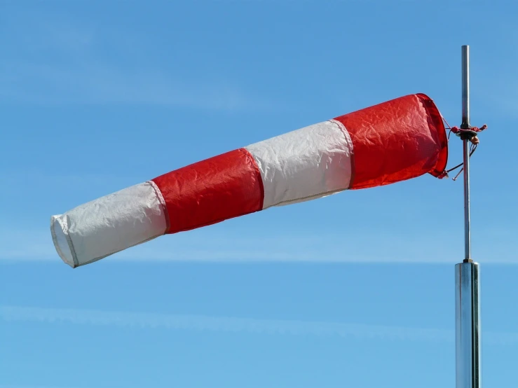 a red and white flag on top of a pole, a picture, plasticien, high winds, inflatable, behaelterverfolgung, turnaround