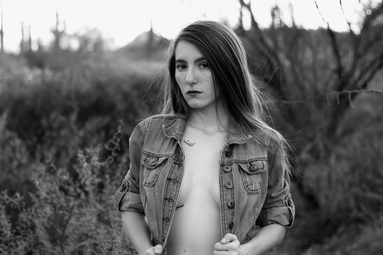 a black and white photo of a woman in a field, a black and white photo, inspired by Dorothea Lange, tumblr, digital art, jacket over bare torso, 🤤 girl portrait, 2 4 year old female model, jean jacket