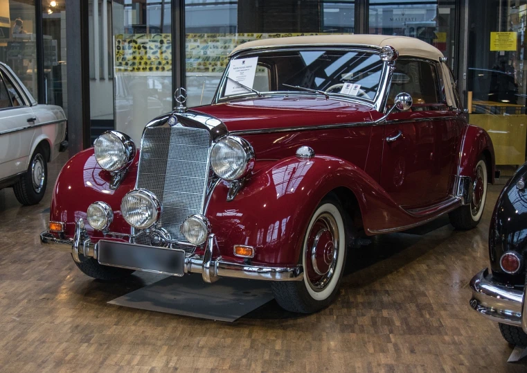 a classic car is on display in a showroom, by Hans Fischer, pixabay, mercedez benz, red brown and white color scheme, 🕹️ 😎 🔫 🤖 🚬, circa 1940s