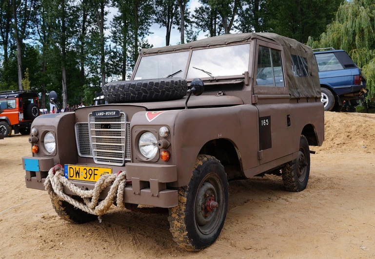 a brown land rover parked on top of a dirt field, a photo, by Jan Tengnagel, pixabay, military parade, with a white muzzle, seventies, high res photo