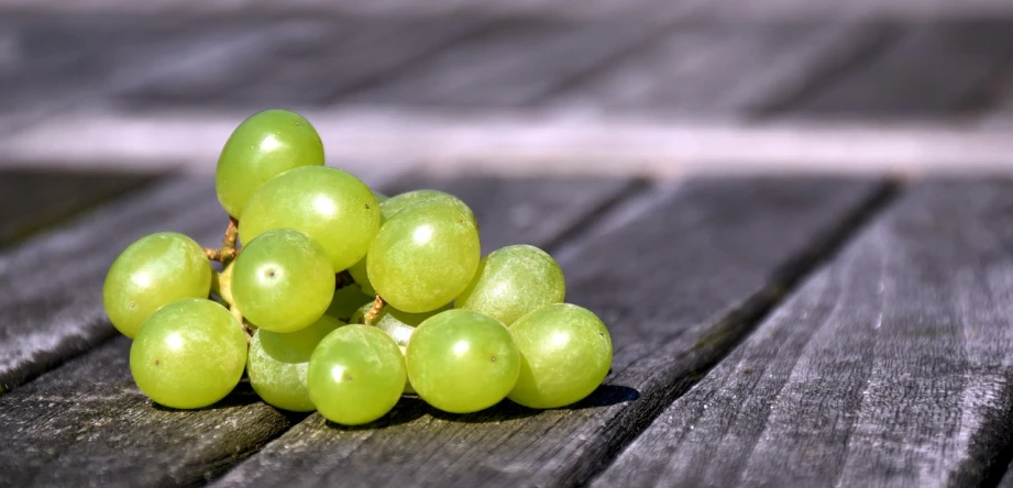 a bunch of green grapes sitting on top of a wooden table, a picture, by Niko Henrichon, test, istock, on a sunny day, whites