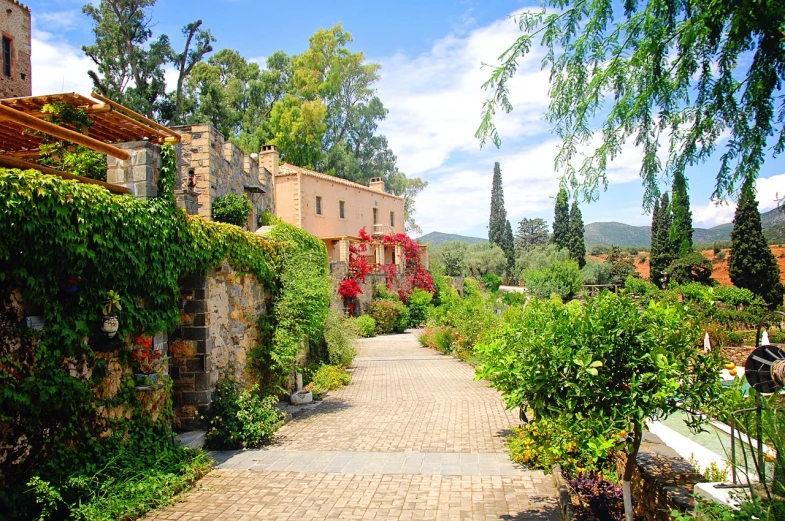 a walkway lined with lots of plants next to a building, by Exekias, pixabay, ancient mediterranean village, beautiful garden on background, ecovillage, driveway