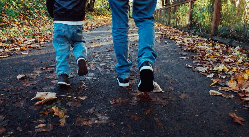 a couple of people that are walking down a road, a picture, pexels, daddy/fatherly, blue jeans and grey sneakers, 🍂 cute, brothers