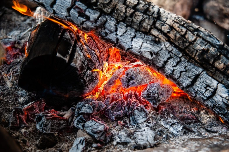 a fire burning in the middle of a pile of wood, a picture, by Alexander Fedosav, covered with tar. dslr, bright orange camp fire, istock, igneous rock